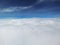 White clouds fluffy under the blue sky. View through the airplane window..