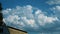 White clouds swirl. Time lapse. White cumulus clouds move rapidly over the slate roof of a house