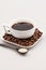 White coffee cup with coffee, plate with coffee beans and teaspoon with sugar