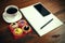 White coffee cup with notebook, four cupcakes, smartphone