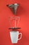 White coffee mug on red background. Metal pour over drip cone pulled apart