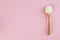 White collagen powder on a wooden spoon on a pink background. Skin care, rejuvenation. Copy space