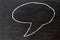 White color chalk hand drawing as speech bubble shape on black b