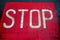 White color stop sign on a red asphalt surface. Warning information for pedestrians