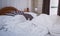 White comfort bed and soft pillow in vintage bedroom with window curtain and lamp. White linen blanket in vintage bedroom. Messy