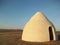 White cone-shaped hut with desert landscape in background