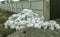 White construction sacks of construction waste are dumped in heap near fence under construction. Pollution concept. Ppile of