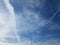 White contrails and clouds in blue sky with street light