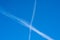 White contrails like X of two planes in clear blue sky. Jet trails on blue sky.