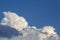 White contrasting clouds backlit by the sun on a blue summer sky. Background.