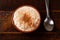 White corn cooked with milk known as canjica, canjicÃ£o or mungunza, in a rustic bowl on wooden table. Typical dish of Brazilian