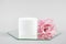 White cosmetic blank jar and pink flower on mirror, gray background. Natural Organic Spa Cosmetic Beauty Concept Mockup, Front
