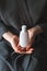 White cosmetic bottle in a female hands, vertical mock-up.