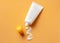 White cosmetic tube with sunscreen cream and squeezed cream texture on orange background.