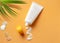 White cosmetic tube with sunscreen cream and squeezed cream texture on orange background.