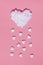 White cotton heart as cloud and small white hearts as rain against pink background. Minimal flat lay love concept.
