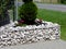 White crashed stone planter in galvanized mesh wire frame with evergreen arborvitae