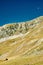 White crescent of the moon rising over the mountain slope with a small wooden structure on a hump