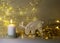 White crocheted Christmas deer Rudolph, white candle and various Christmas decorations, illuminated background of a chain of white