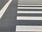 White crosswalk sign on grey asphalt road with a white straight line