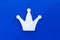 .White crown on a blue background. Decor element, a symbol of power, wealth. Headdress of monarch. The king of chess..