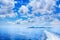 White cumulus clouds in blue sky over sea landscape, many clouds above ocean water panorama, ship trail, island on horizon line