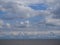 White cumulus clouds in a blue sky over a seascape, a large number of clouds over a panorama of ocean water, cloudy weather