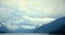 White cumulus clouds descend between the mountains to the morning lake