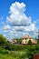 White Cumulus clouds float across the blue sky above the houses. Beautiful atmospheric phenomenon. Natural vertical background