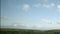 White cumulus clouds are moving fast in the blue sky over the green Irish hills, timelapse video