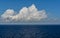 White cumulus clouds in sky over blue Baltic sea water landscape, with vague silhouette of Finland in the horizon