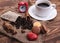 White cup of black coffee, heart, beans, macaroons, cinnamon and clock on the wooden background