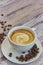 White cup with black coffee with milk. Handful of coffee beans on a wooden table. vertical view of drink with coffee. Copy space