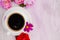 White cup of black coffee and rose petals beside