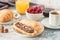 White cup of black tea with croissant or toasts with peanut butter, chokolate paste , jelly or jam on white wooden table, Breakfas