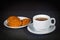 White cup with black tea and oatmeal cookies on a white saucer