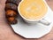 White cup of cappuccino, fresh croissant on wooden table. Latte, macro, top view