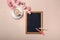 White cup with cappuccino, sakura flowers, chalk board on a past