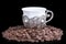 White cup with coffee beans on black background