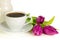 White cup of coffee with bunch of purple tulips on white background