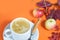 White cup of coffee with cappuccino cream on an orange background with autumn leaves, apples and red berries. Fall