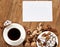 White cup of coffee and cookies on wooden background, spice and decoration, blank paper sheet for text, top view