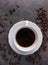 White cup of coffee on dark grey beton background decorated with coffee beans.