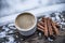 White cup of coffee with foam cinnamon sticks, on snow flakes wi