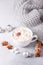 White cup with coffee and marshmallow, sweater, cinnamon. Cozy christmas composition. Hygge concept Soft focus