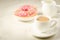 White cup coffee with milk and fresh sugary pink donut/white cup coffee with milk and fresh sugary pink donut on a white marble