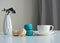 White cup of coffee, multicolored macaroons, vase with a sprig of dried berries on white background, close up