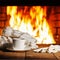 White cup of coffee or tea, woolen scarf, gloves and cap on wooden table near fireplace.