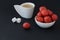 White cup of coffee, two pieces of sugar and little round plate with juicy tasty strawberries, one strawberry lies separately on b