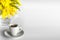 White cup of coffee and a vase of branches of mimosa on a white background